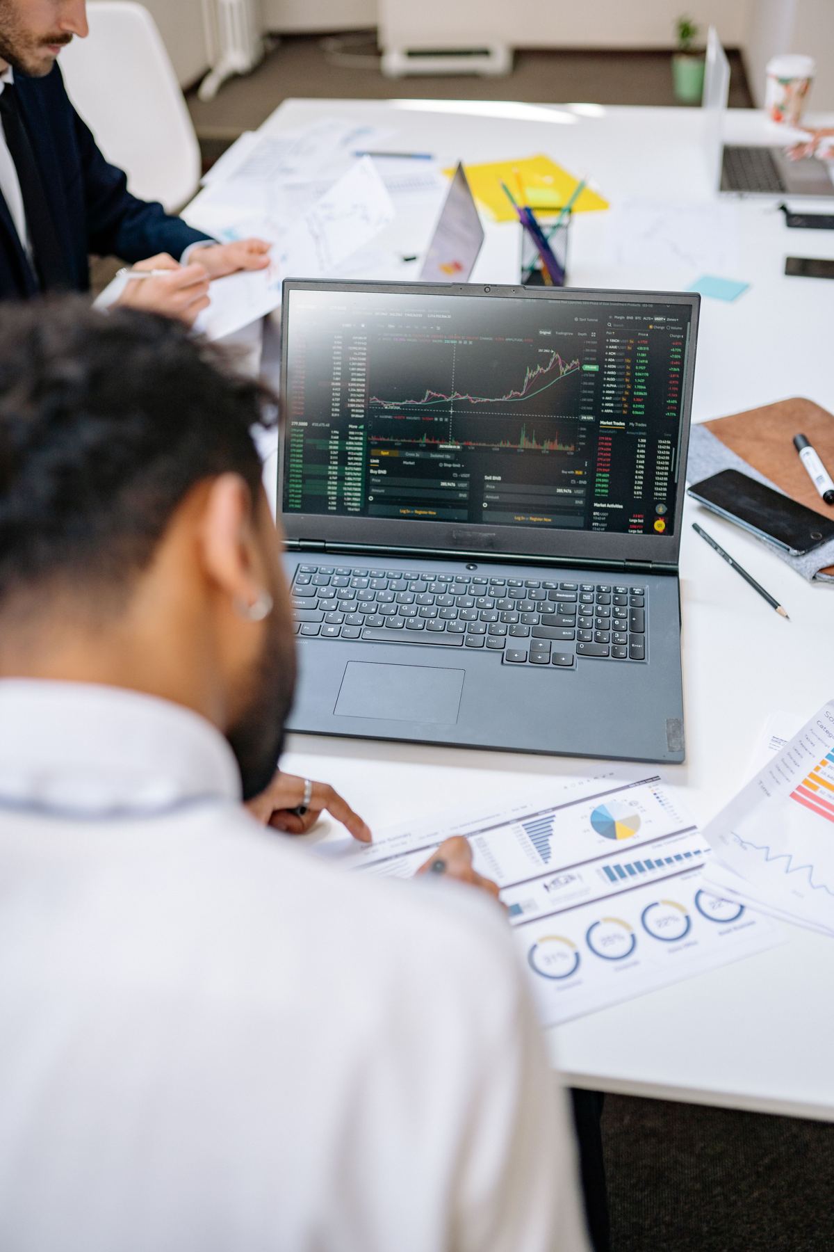 Analyst reviewing financial charts on a laptop next to printed reports